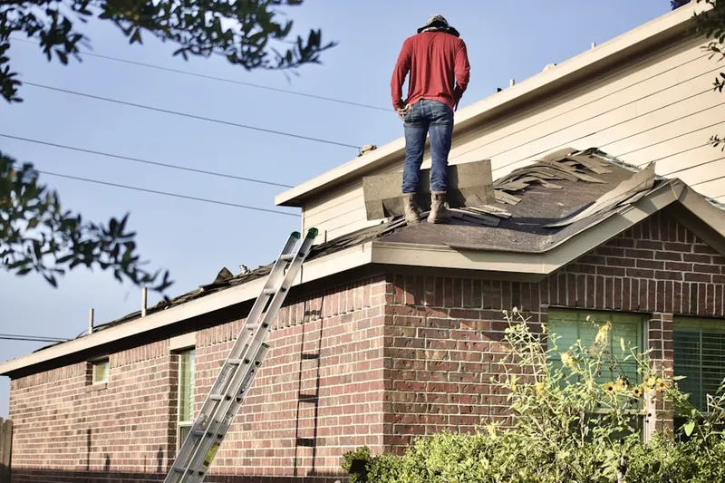 Professional roofer working on a residential roof in Malone
